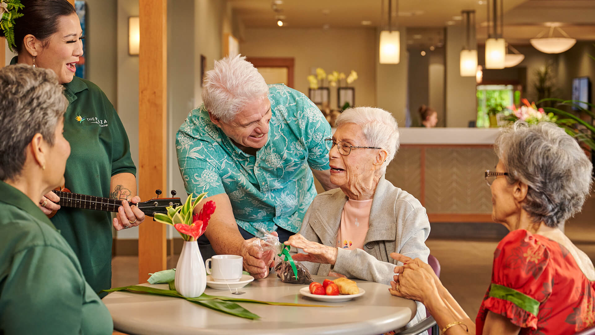 Staff member playing ukulele for residents and family at The Plaza Assisted Living.