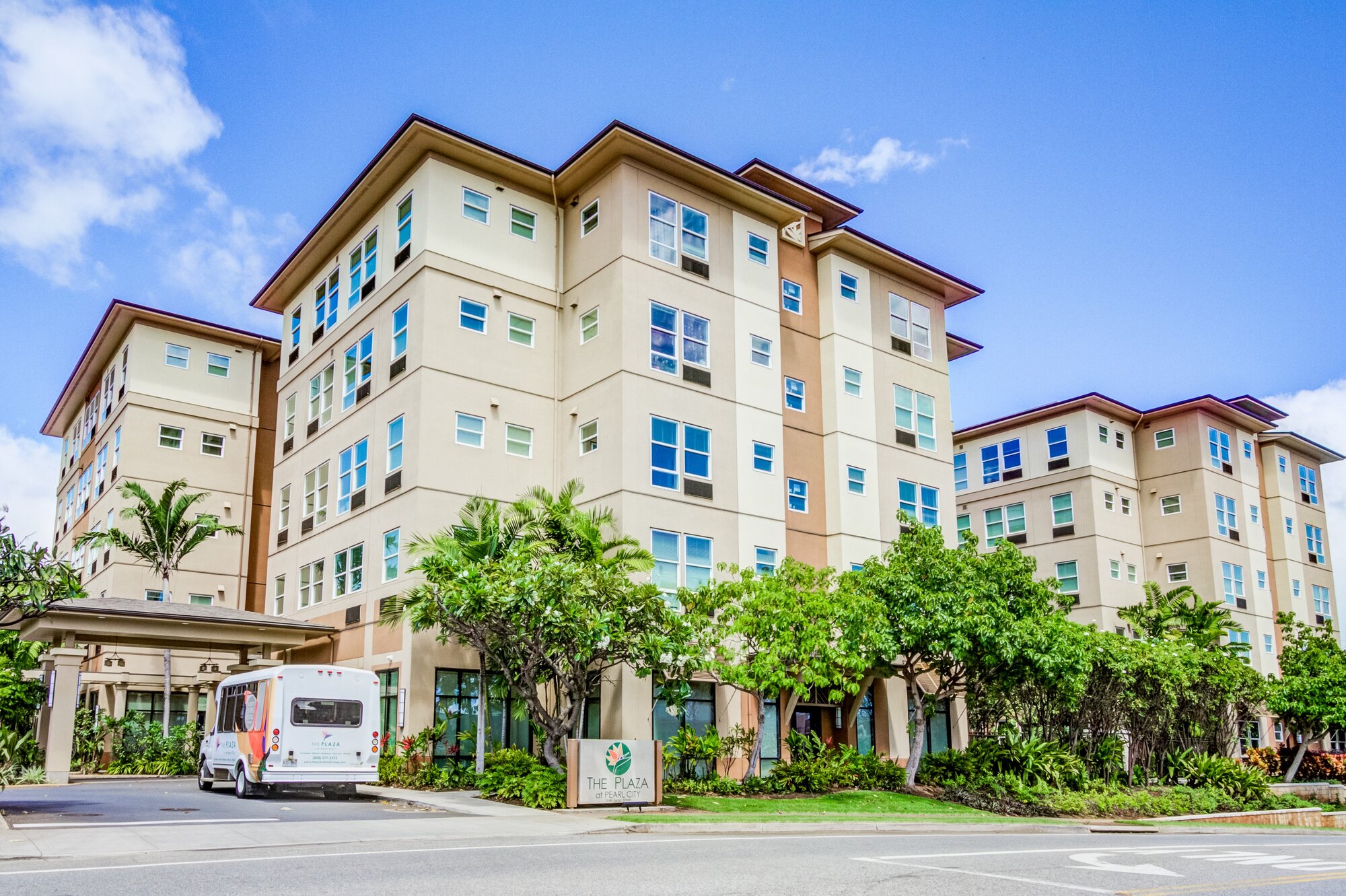Multi-story exterior of The Plaza Assisted Living at Pearl City with facility shuttle.