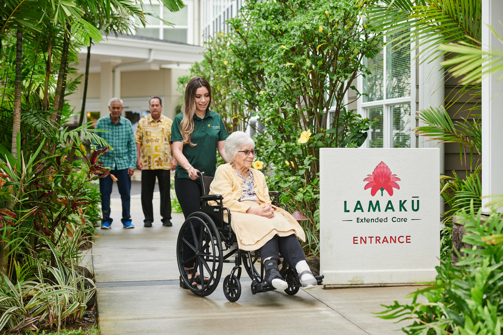 Staff pushing a resident toward the Lamakū Extended Care entrance.