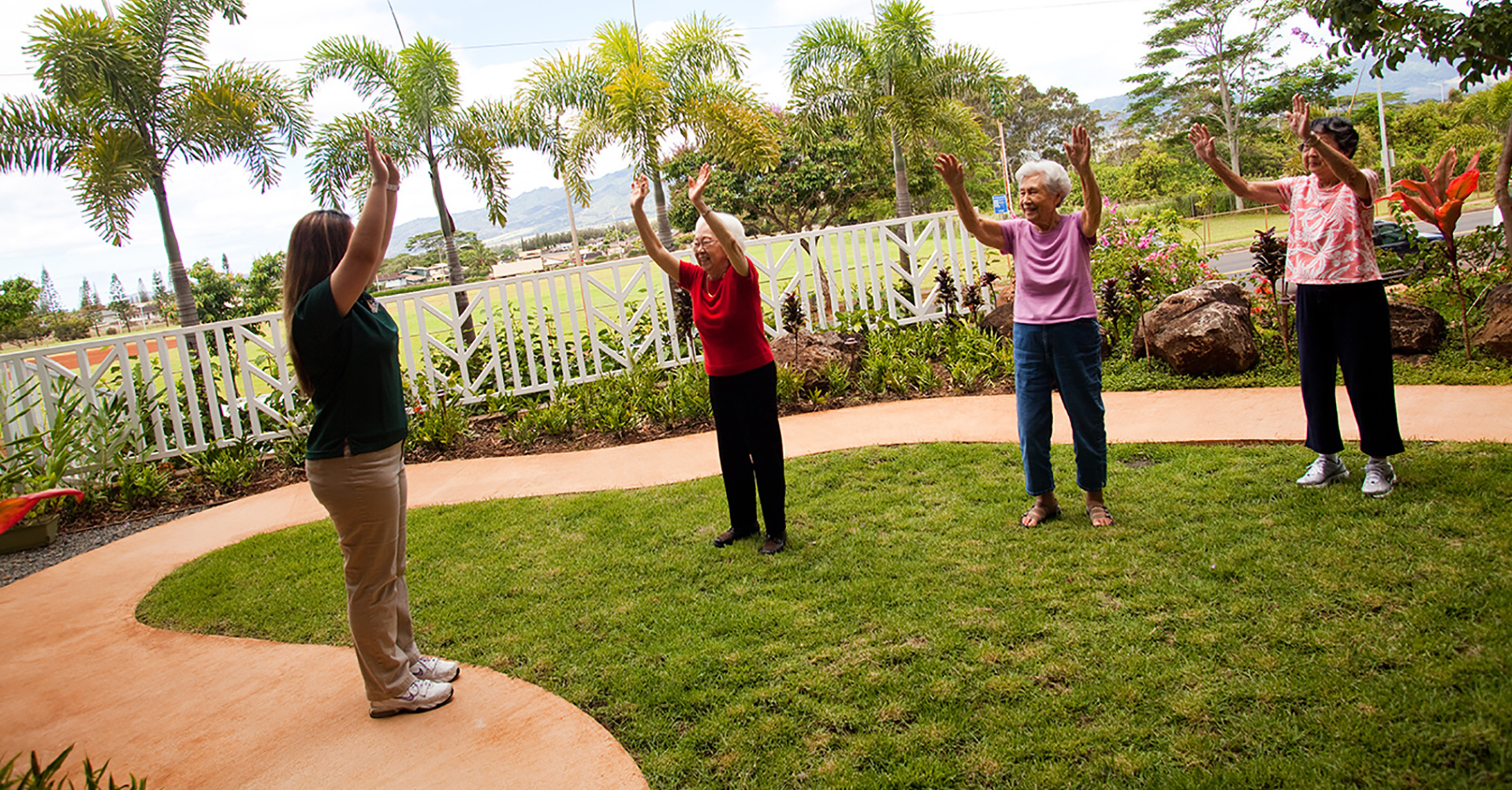 Residents practicing Tai Chi in a lush outdoor garden at The Plaza Assisted Living.