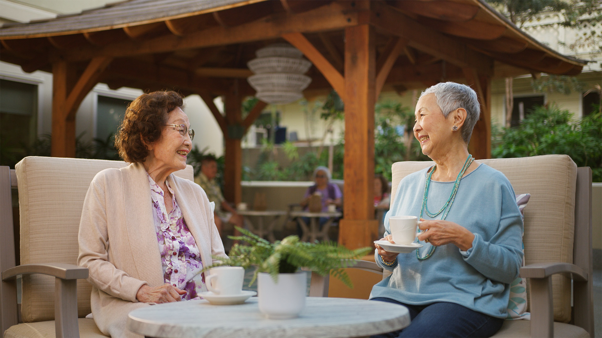 Two senior women talking in an outdoor courtyard.
