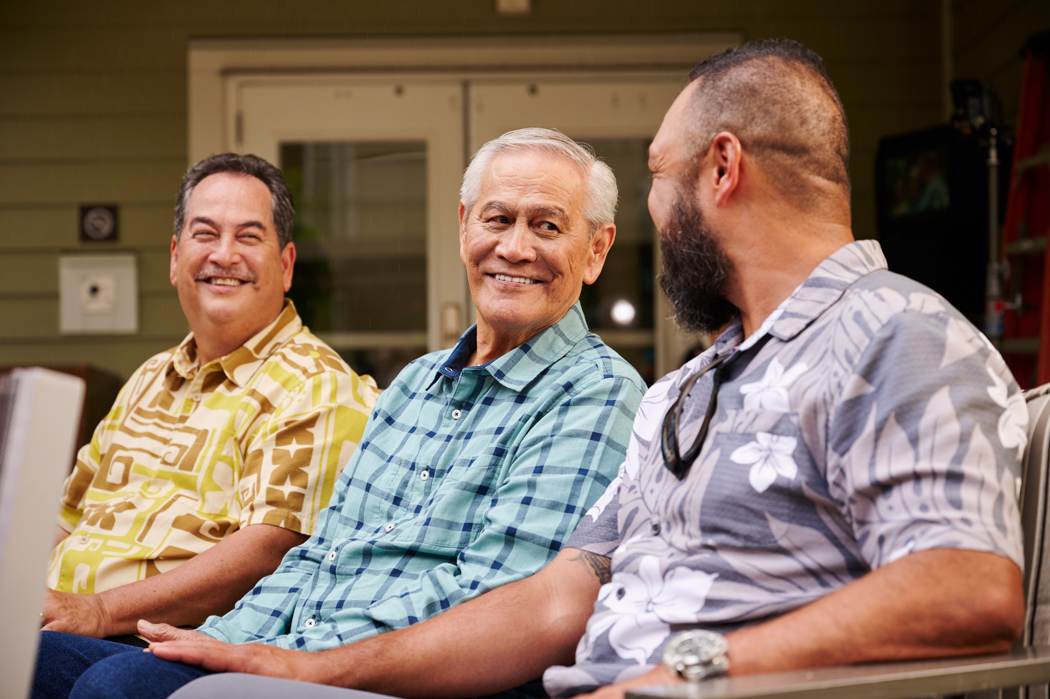 Three men talking and laughing in an outdoor courtyard.