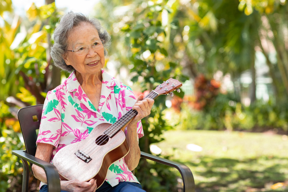 Resident playing ukulele in the sun at The Plaza Assisted Living.