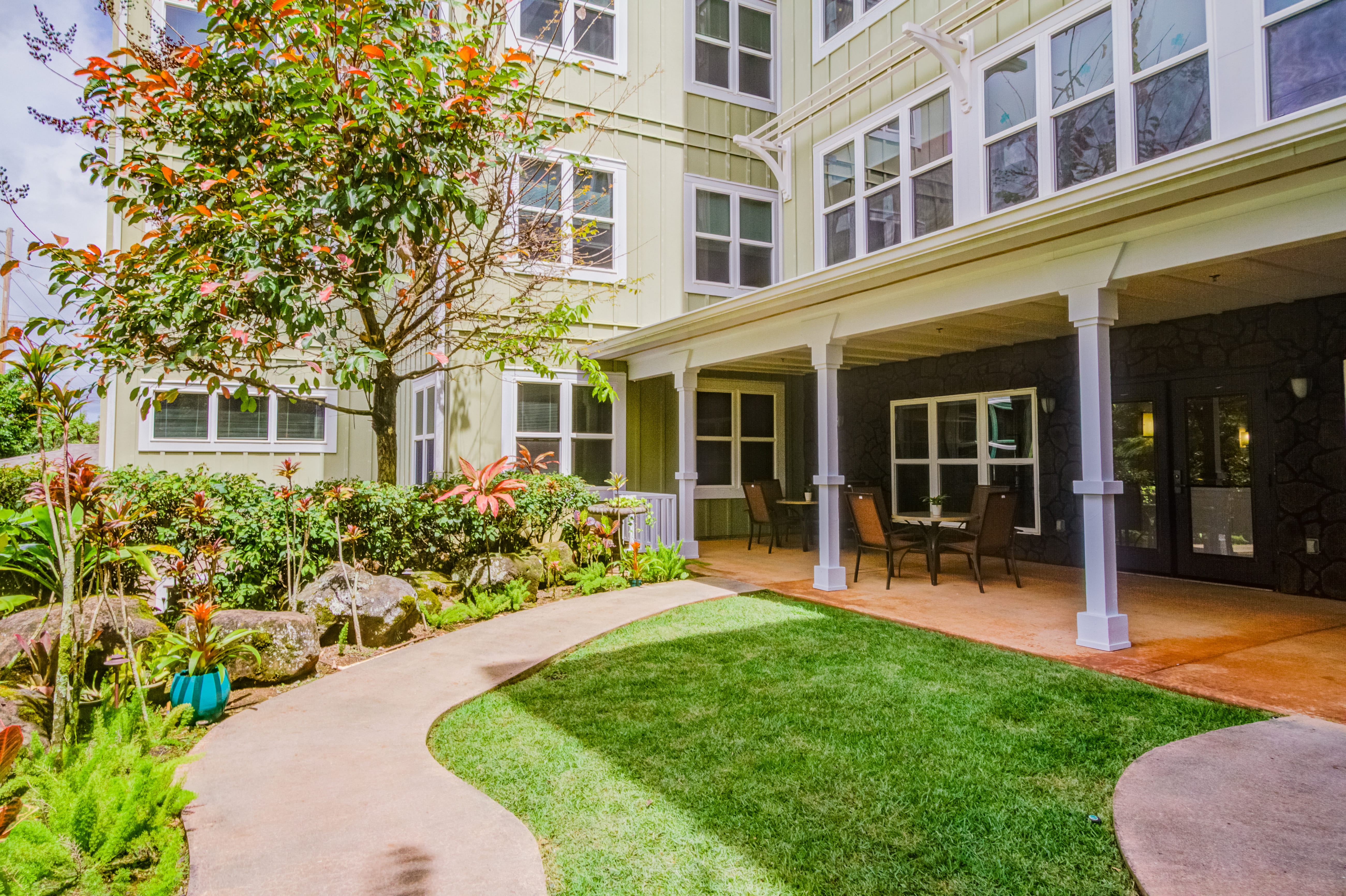 Covered patio and lush green lawn at The Plaza Assisted Living Mililani.