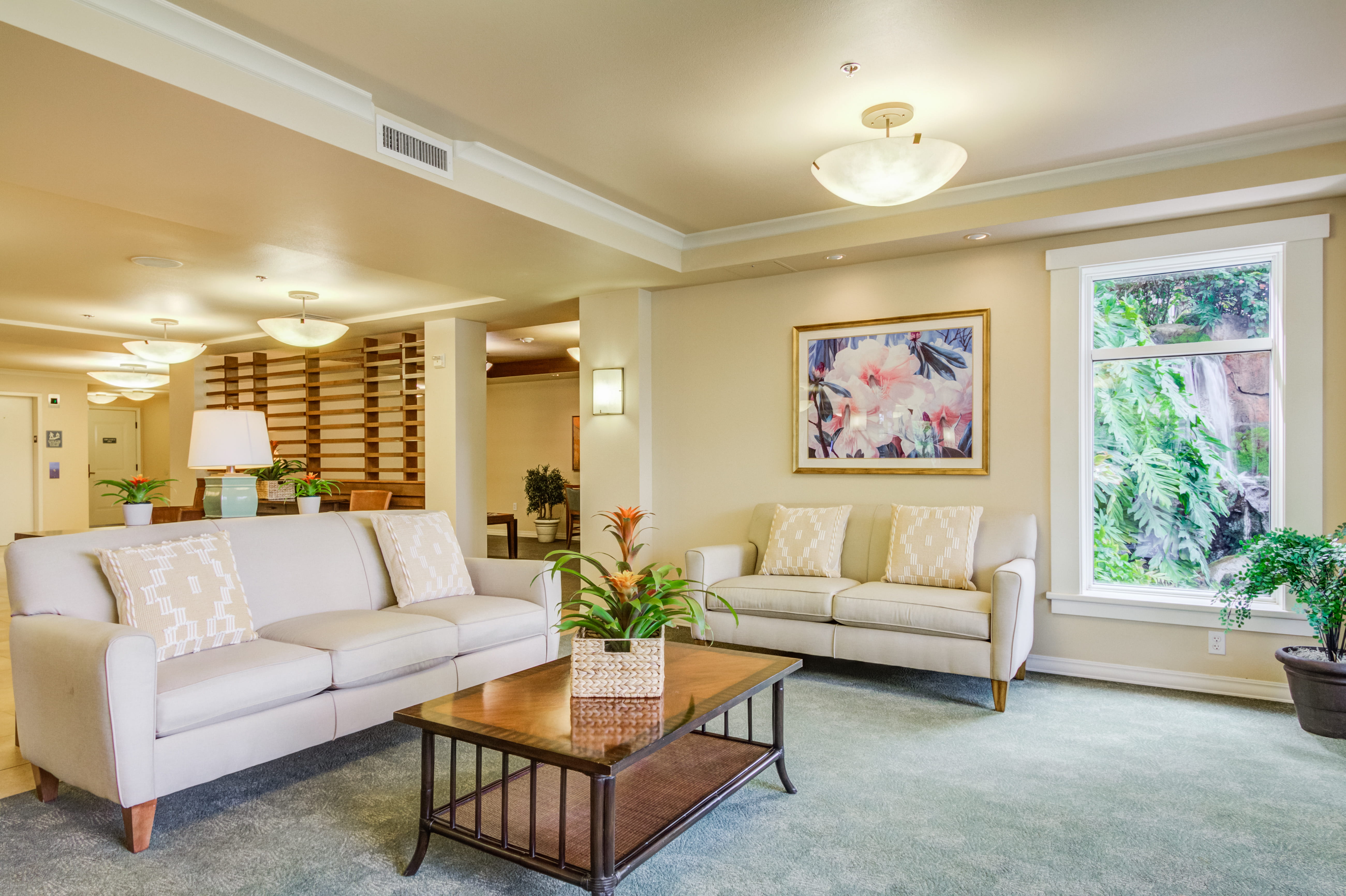 Lounge area with a coffee table and a scenic waterfall view through the window.