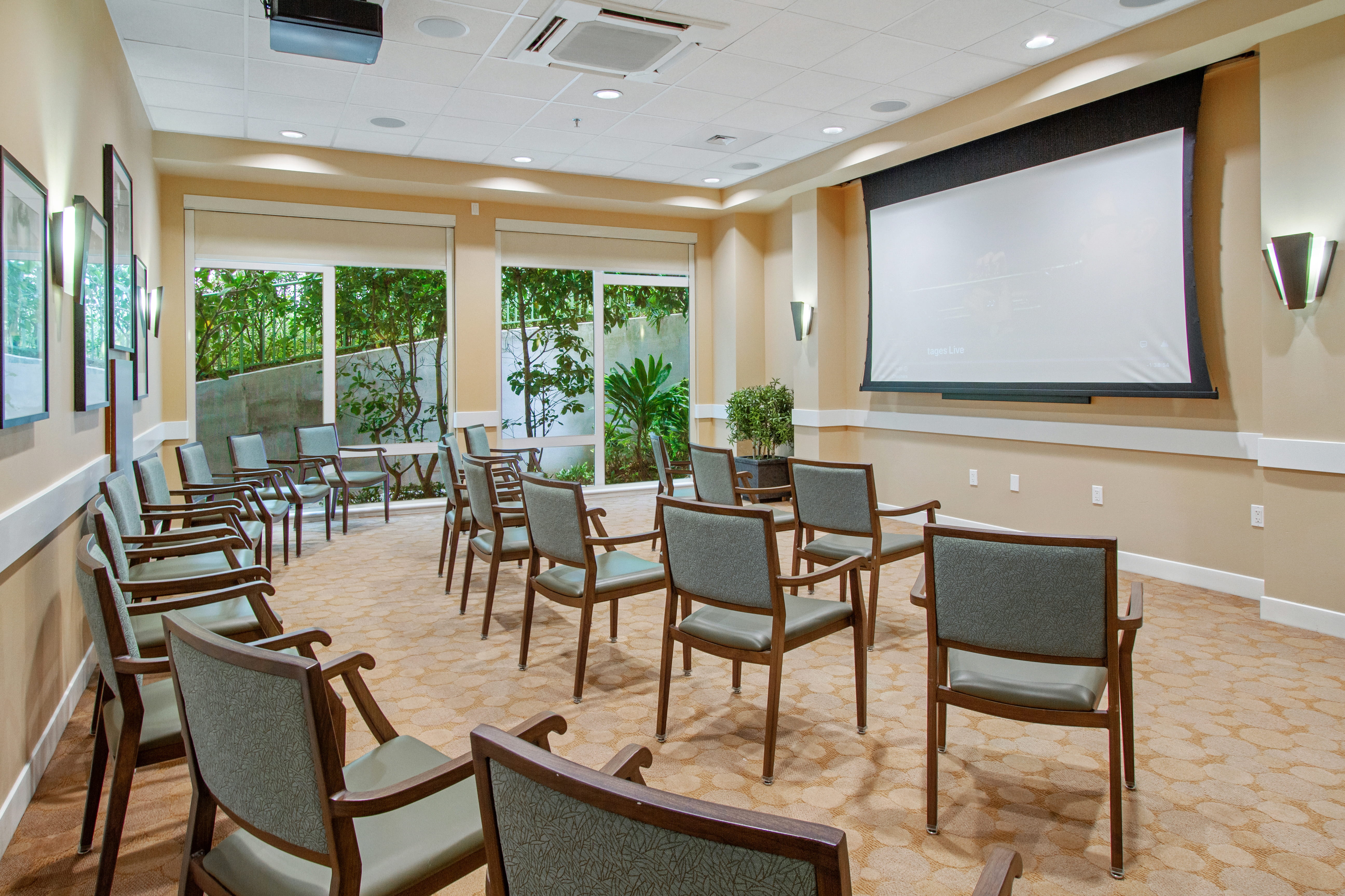 Resident theater room at The Plaza Assisted Living Moanalua with rows of chairs and a large screen.
