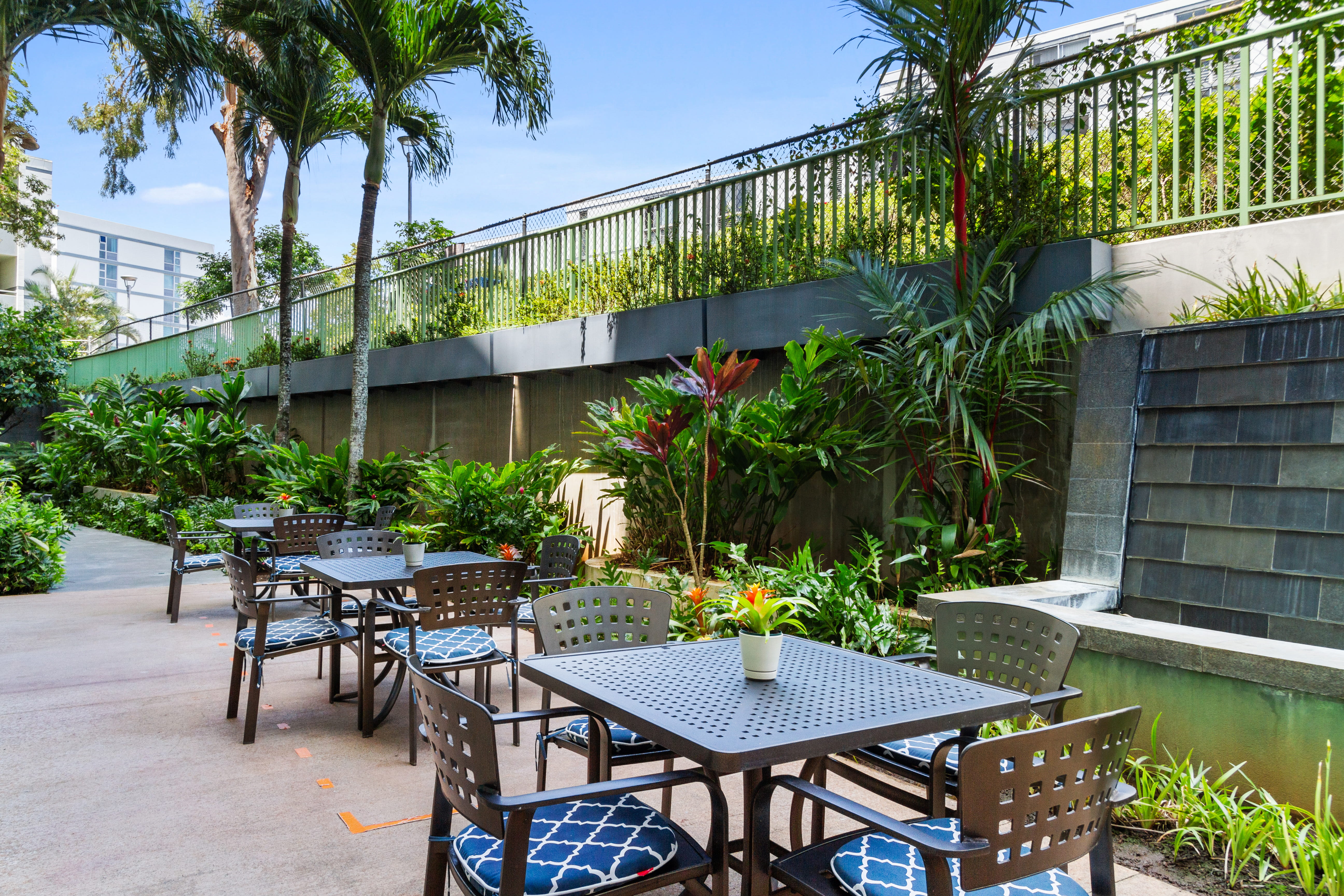 Outdoor tables and chairs next to a stone water feature at The Plaza Assisted Living.