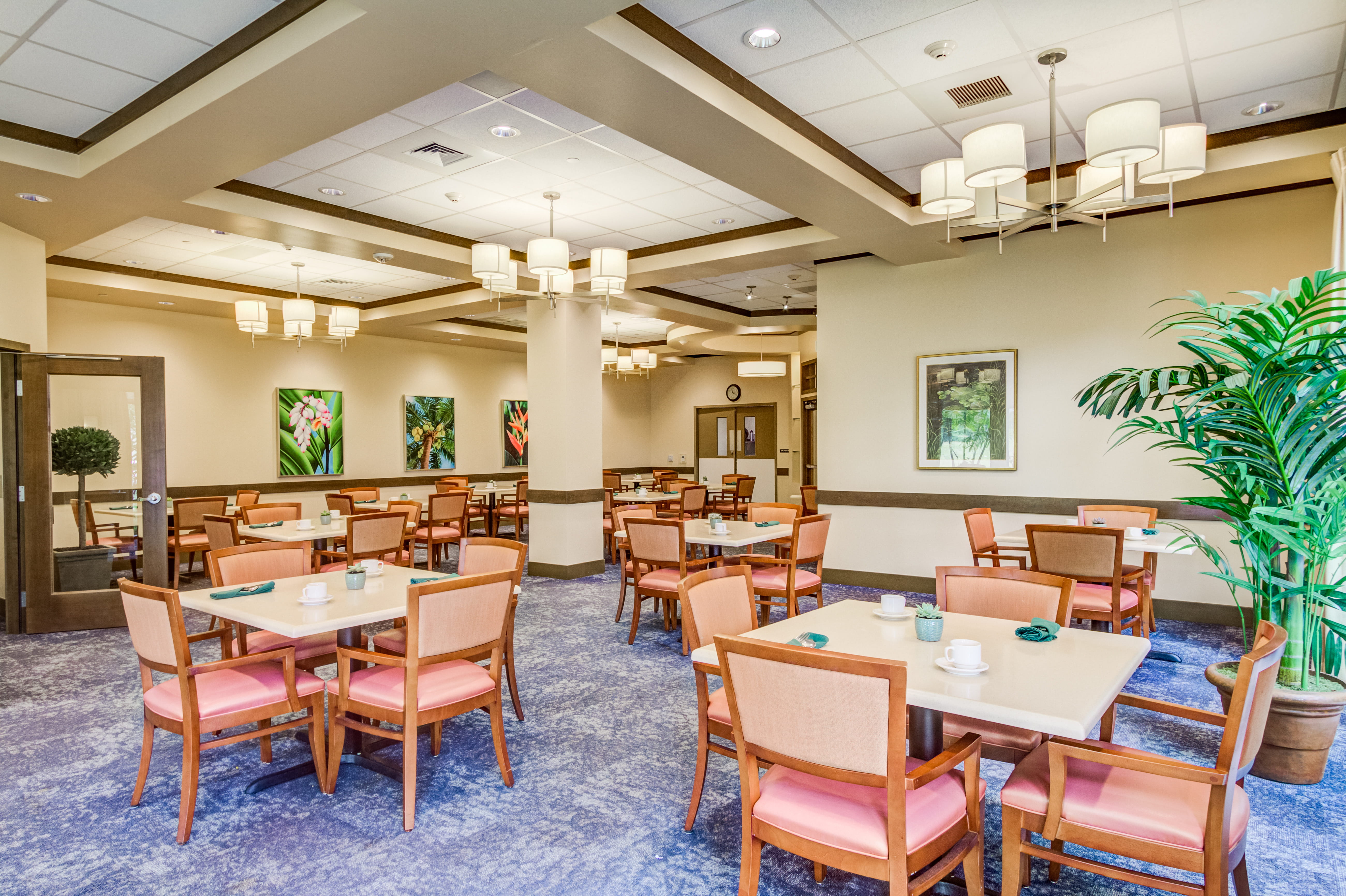 Spacious dining room at The Plaza Assisted Living with elegant chandeliers.