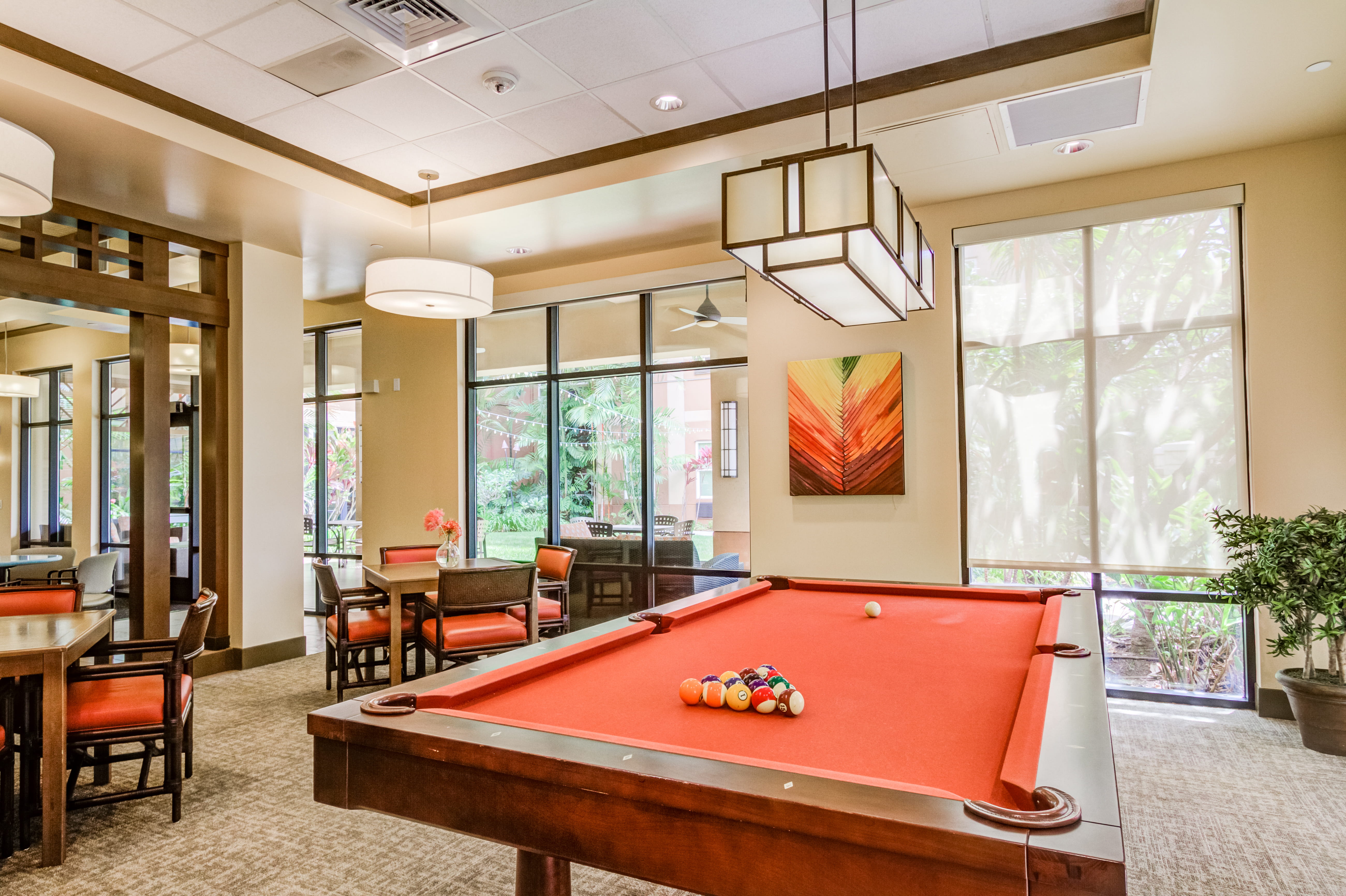 Recreation room with a red pool table and social seating at The Plaza Assisted Living.