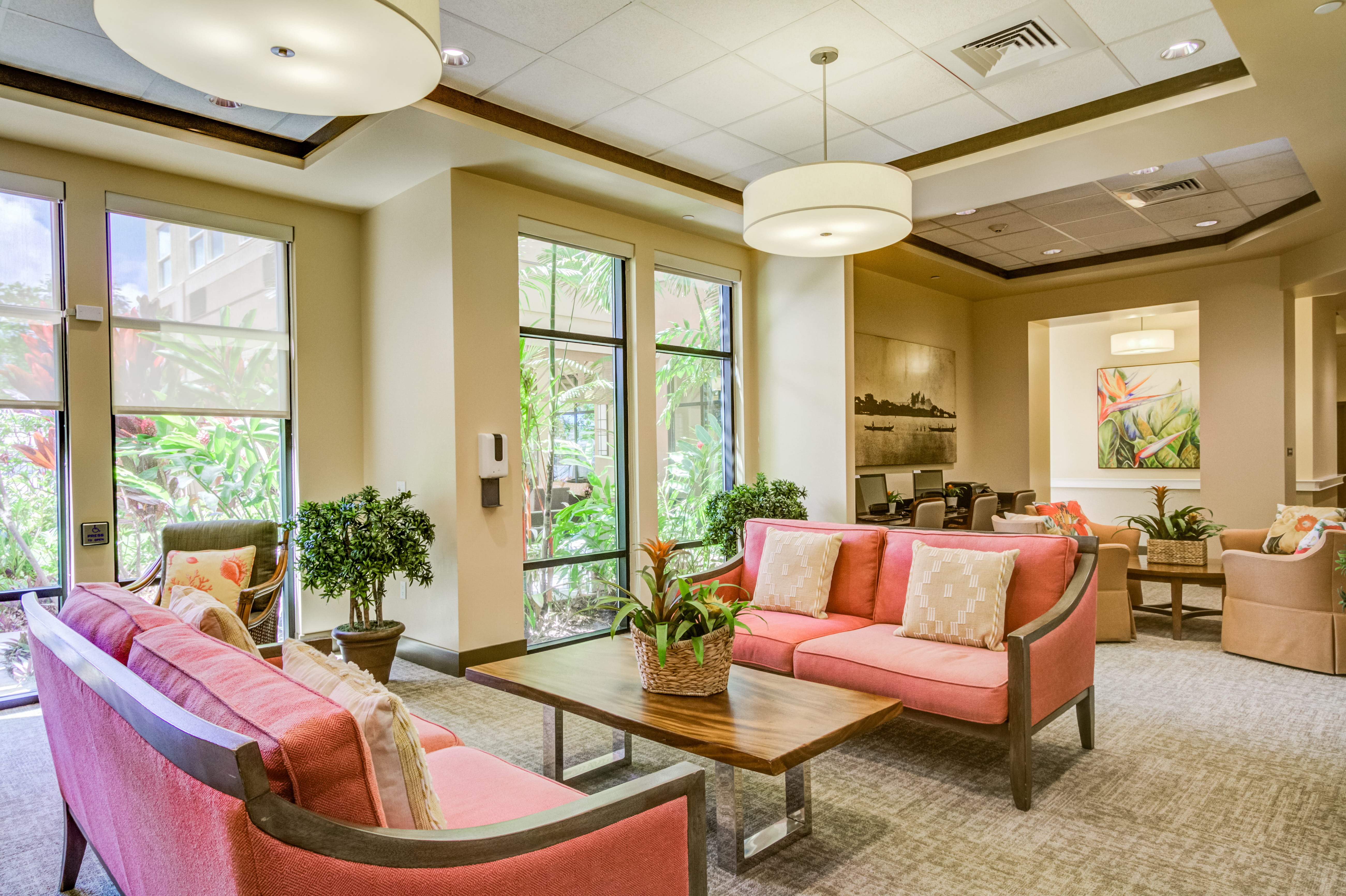Lobby lounge with pink sofas and bright windows at The Plaza Assisted Living Pearl City.