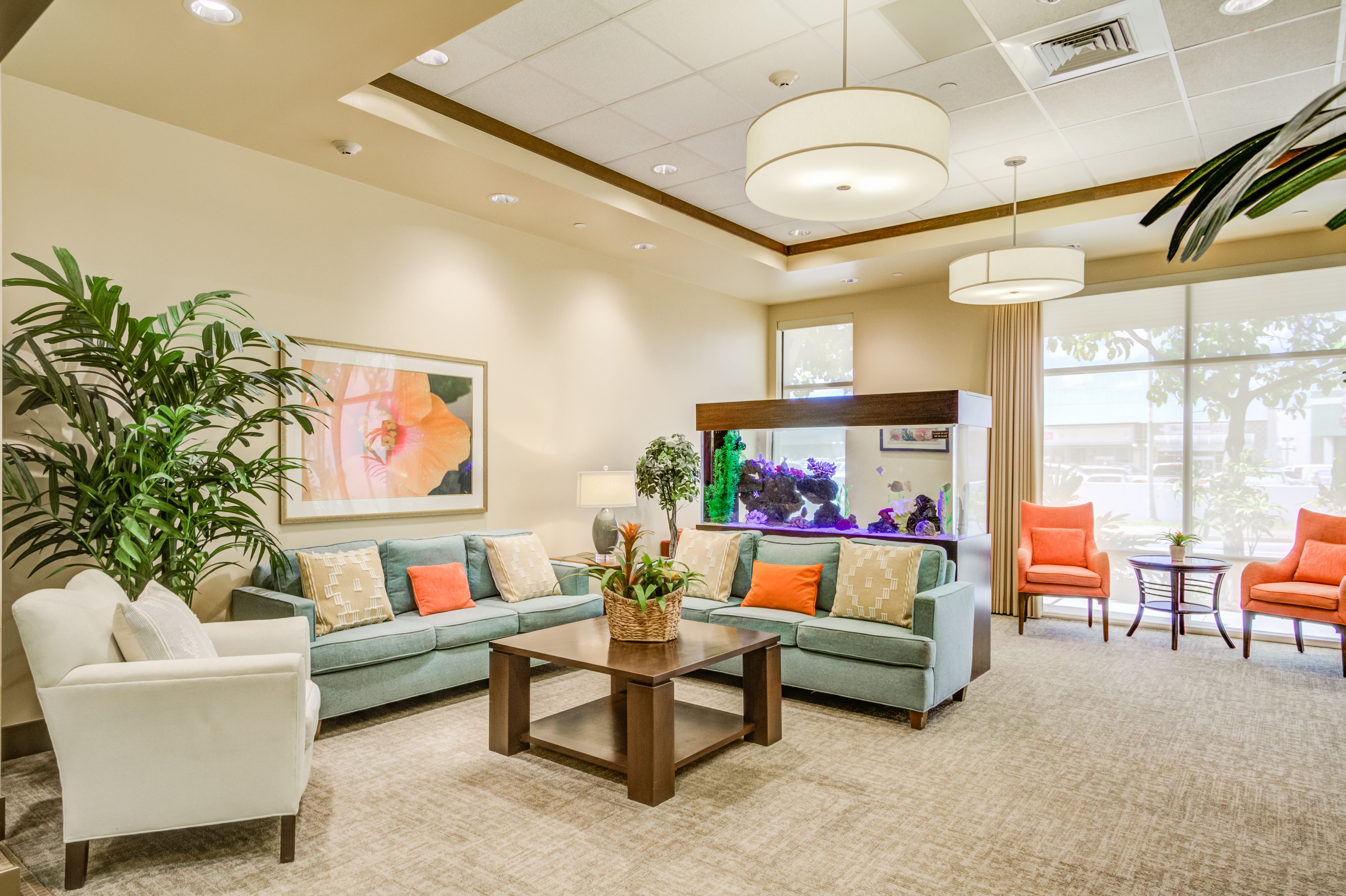Lobby lounge at The Plaza Assisted Living with comfortable sofas and a large aquarium.