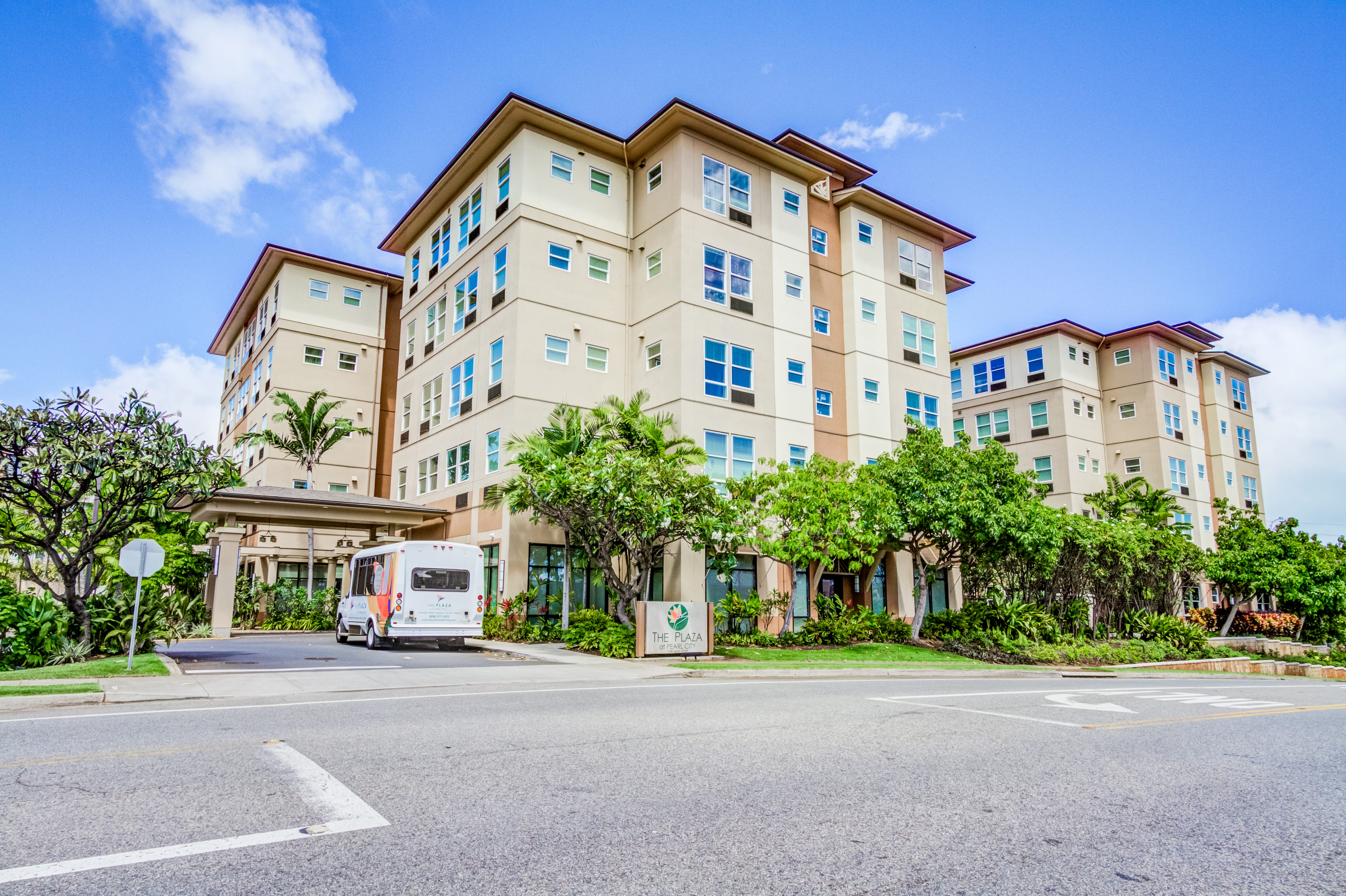 Exterior view of The Plaza Assisted Living building with a resident shuttle bus.