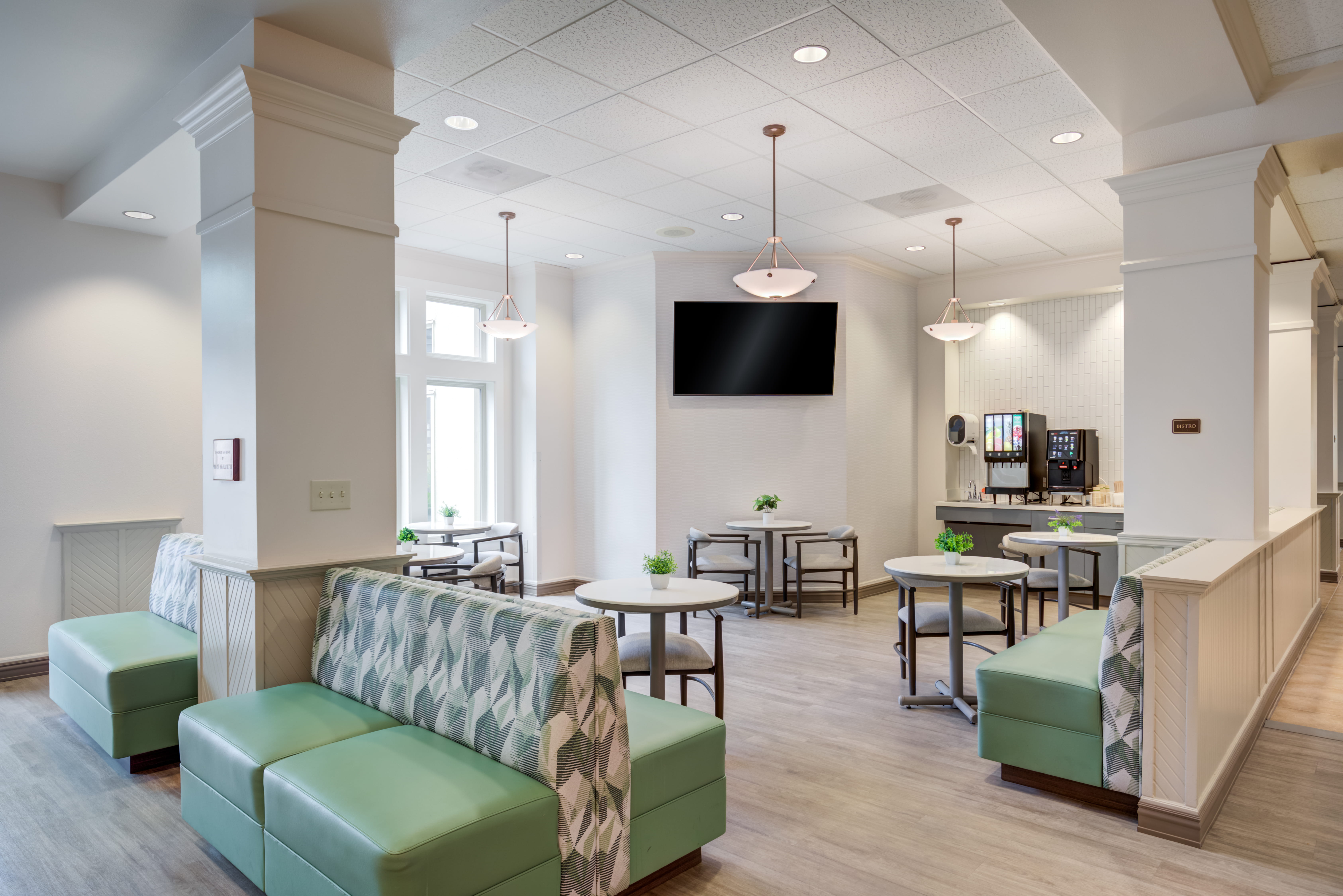 Bistro area with green seating and a coffee station at The Plaza Assisted Living.