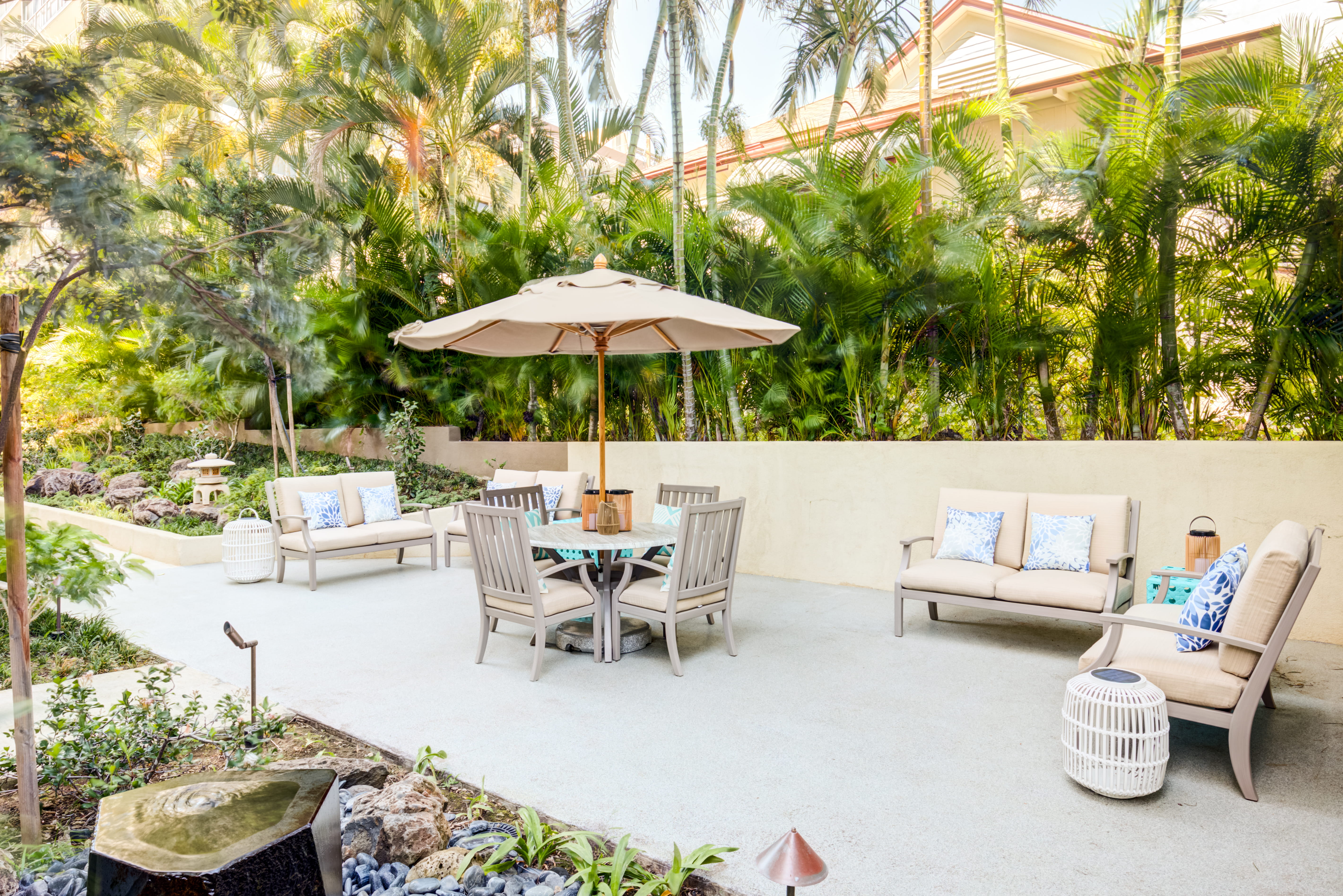 Outdoor patio with comfortable seating and an umbrella at The Plaza Assisted Living.
