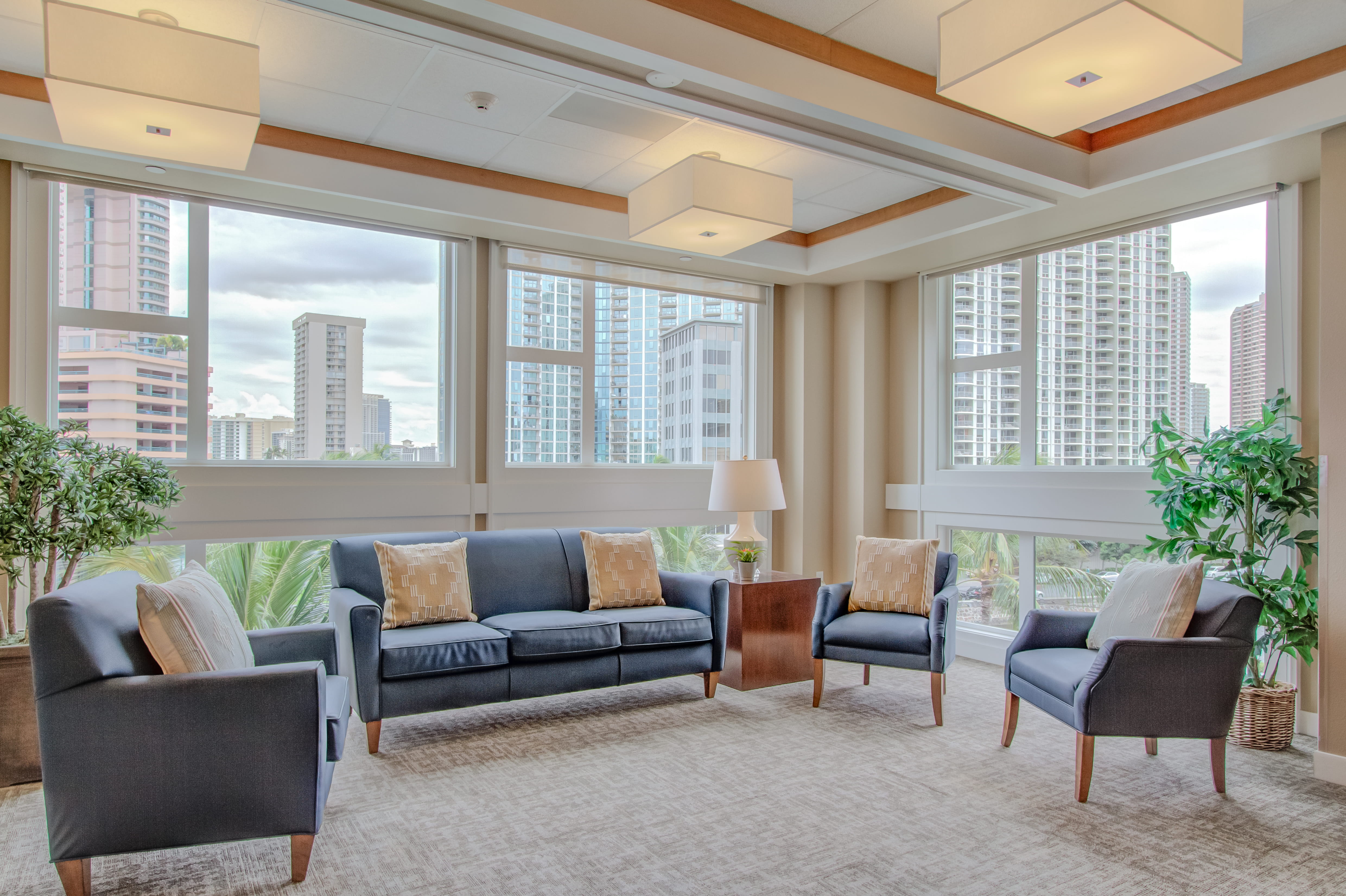 Blue sofa and armchairs in a lounge overlooking the Waikiki skyline.
