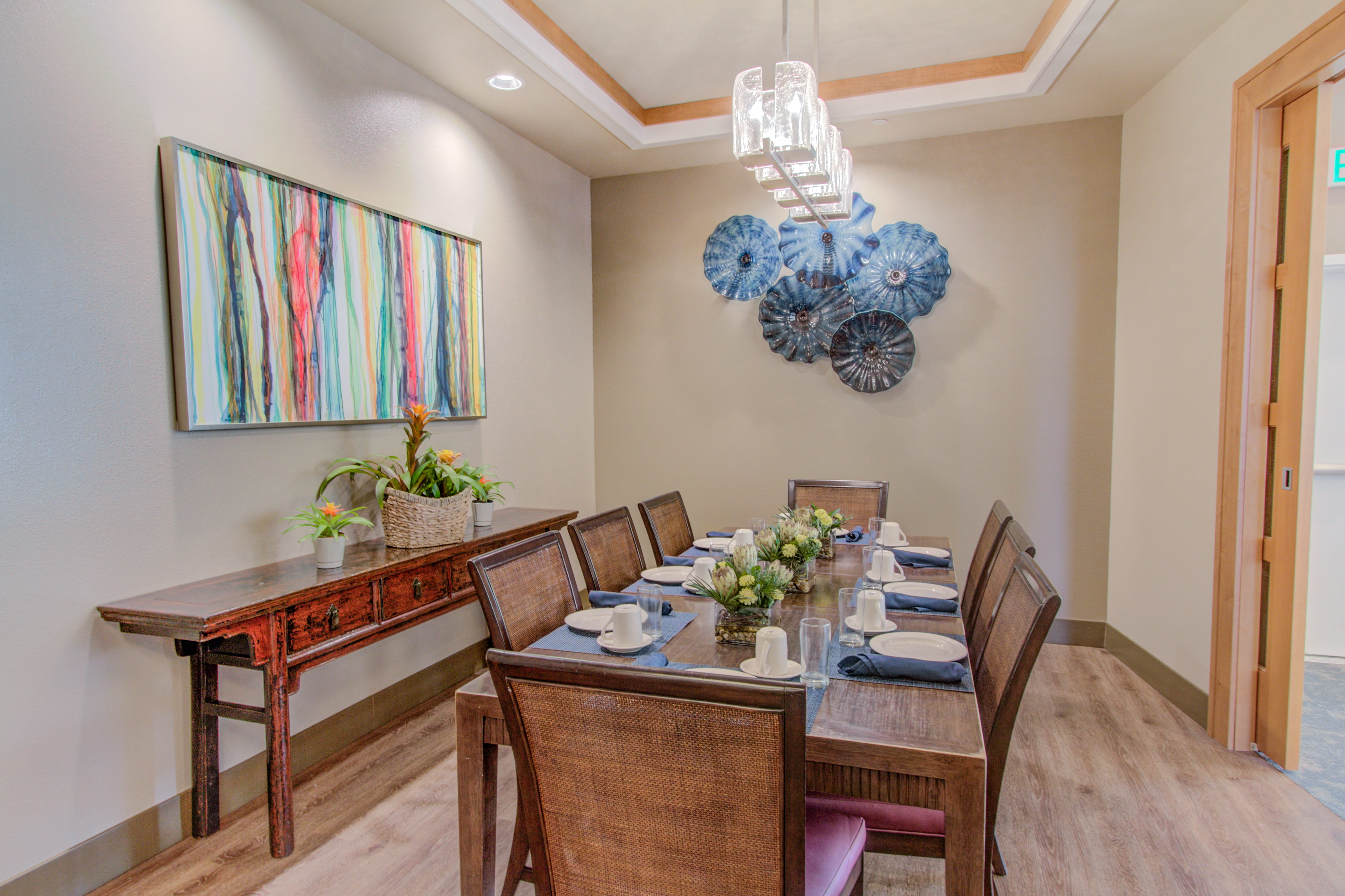 Private dining room with high-back wicker chairs and blue glass wall art.