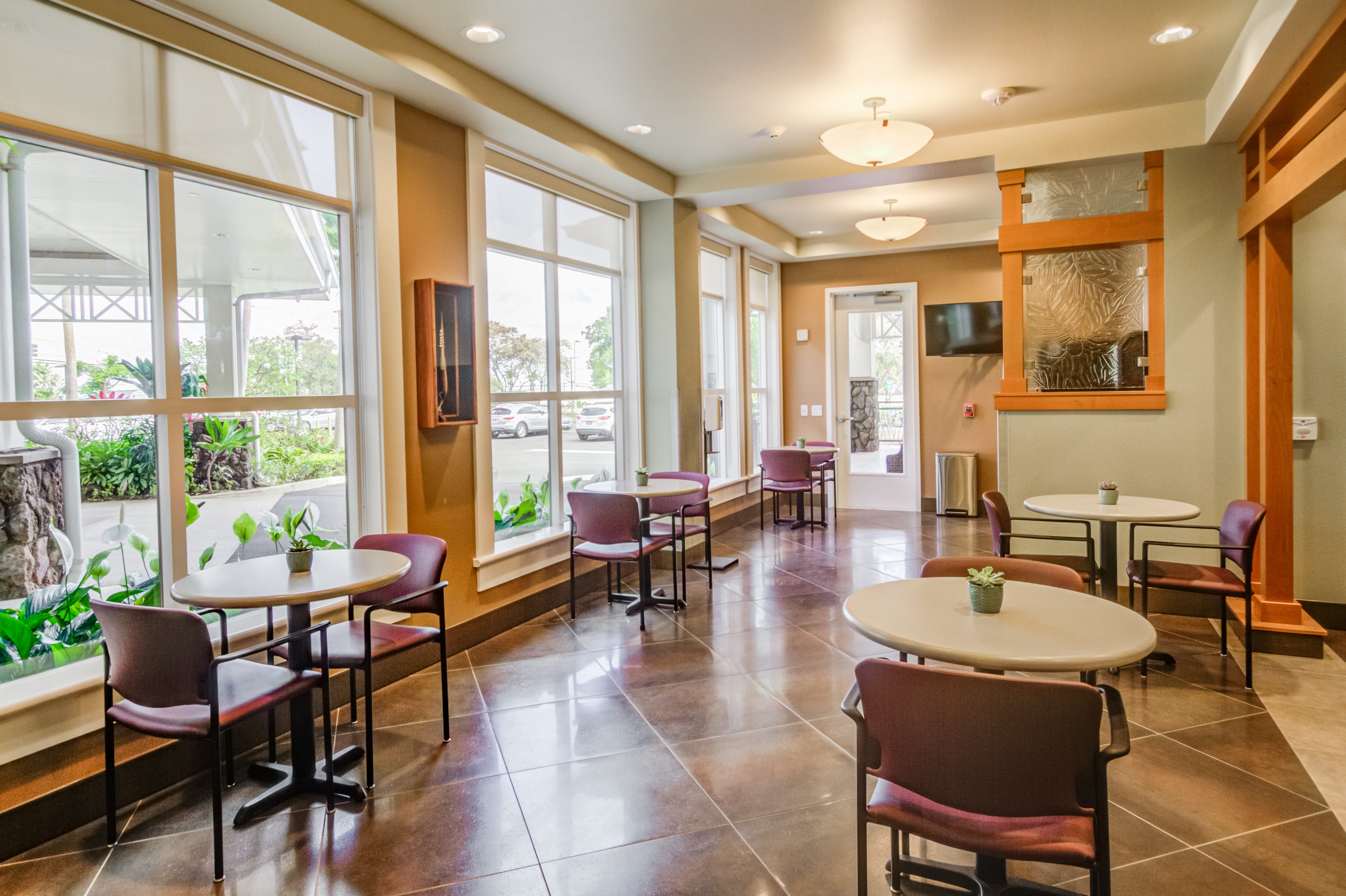 Café seating area with large windows at The Plaza Assisted Living.
