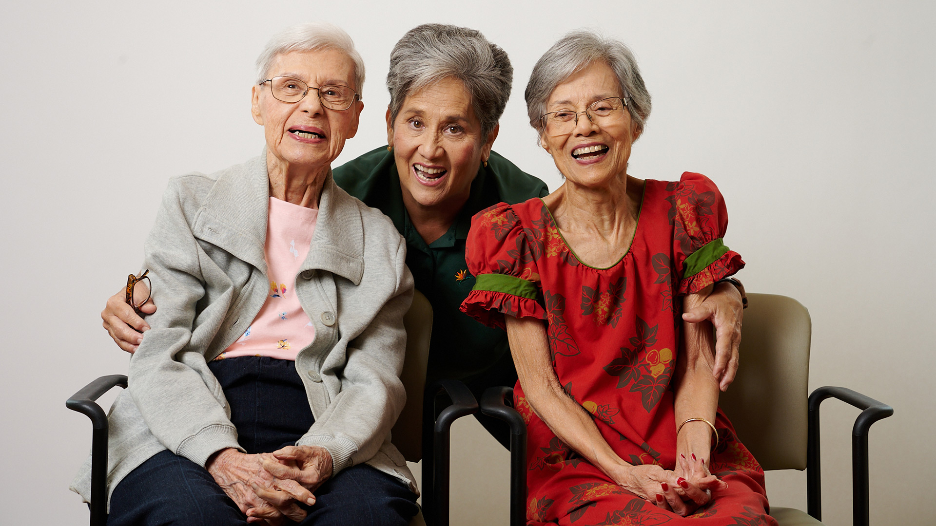 Three cheerful residents posing together at The Plaza Assisted Living.